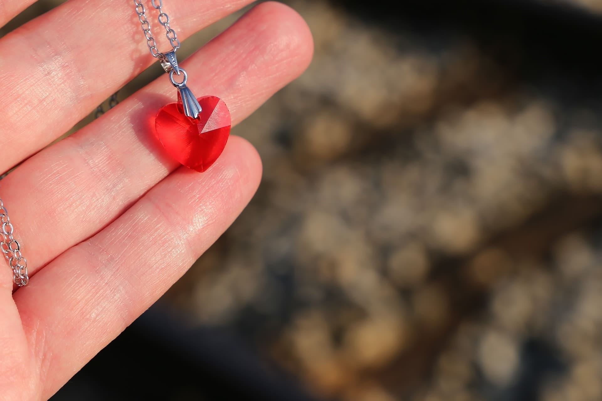 Рука медальон. Медальон в руке. Медальон символ любви. Медальон сердце красное. Камень сердце в руке.